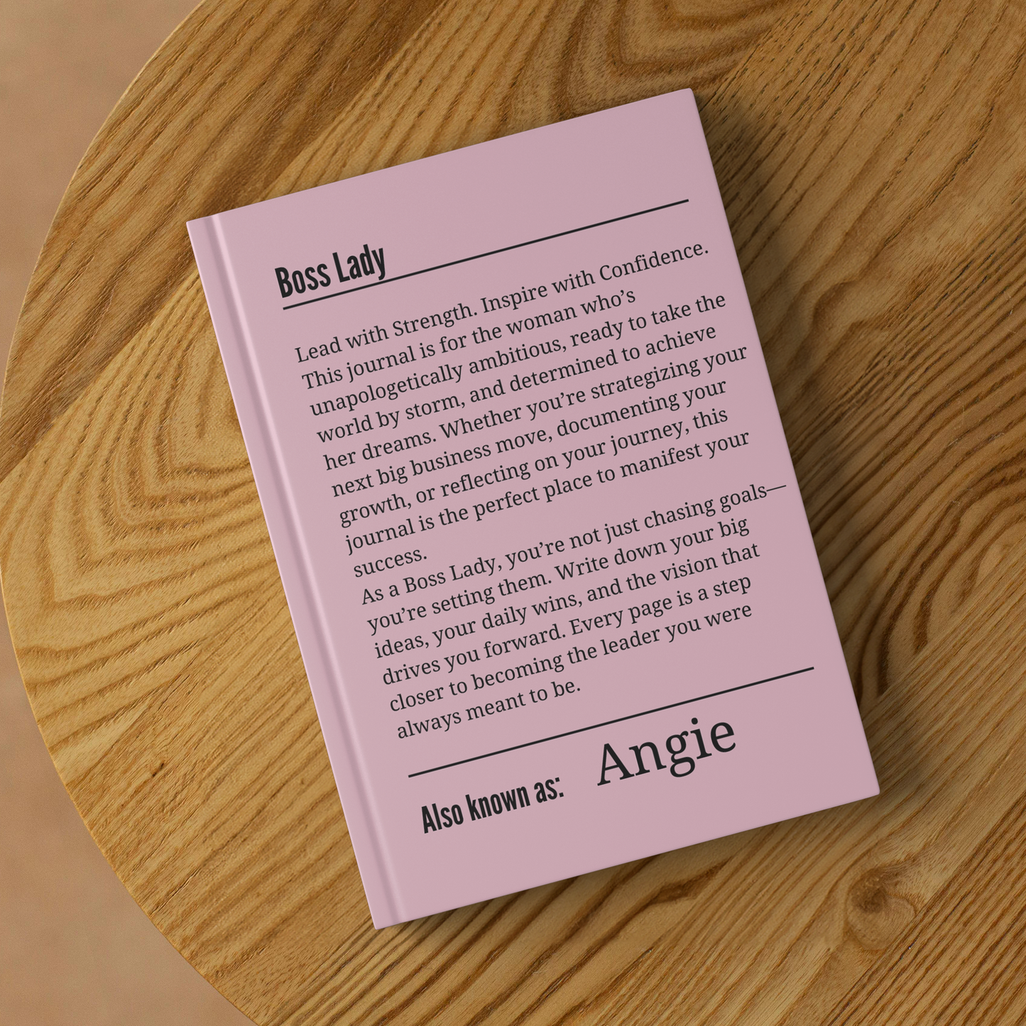 Pink Boss Lady journal with motivational quote and customizable name on wooden surface.