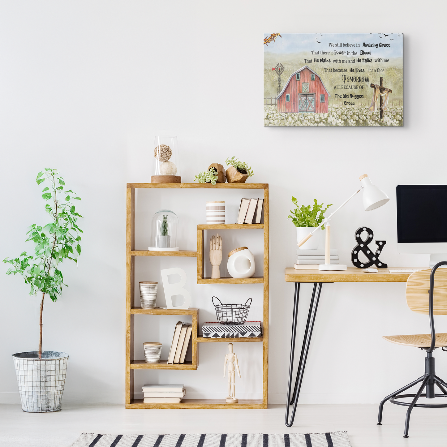 Canvas wall art with "We Still Believe in Amazing Grace" text and rustic red barn design above a white desk and wooden.