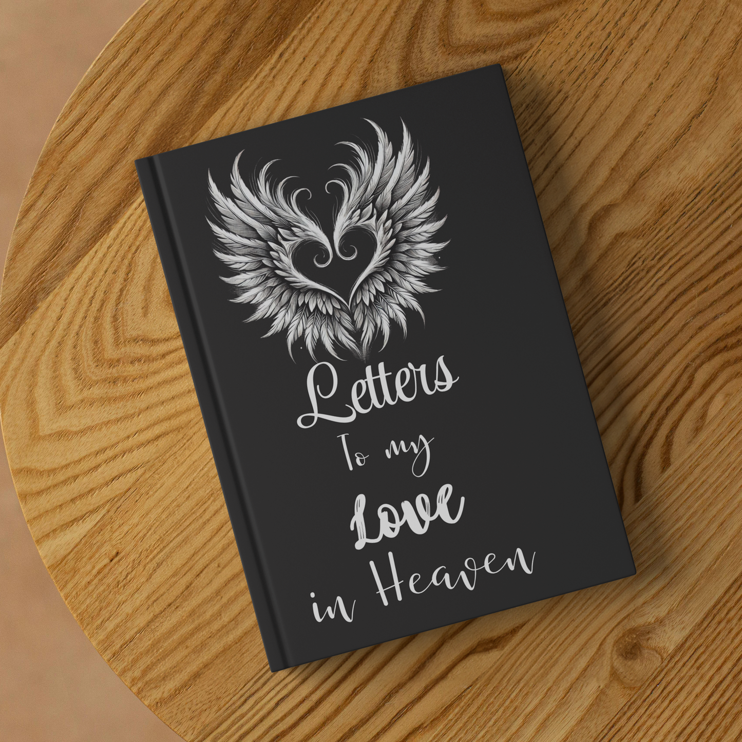Black hardcover journal with white winged heart design and script text "Letters to my Love in Heaven" on cover.