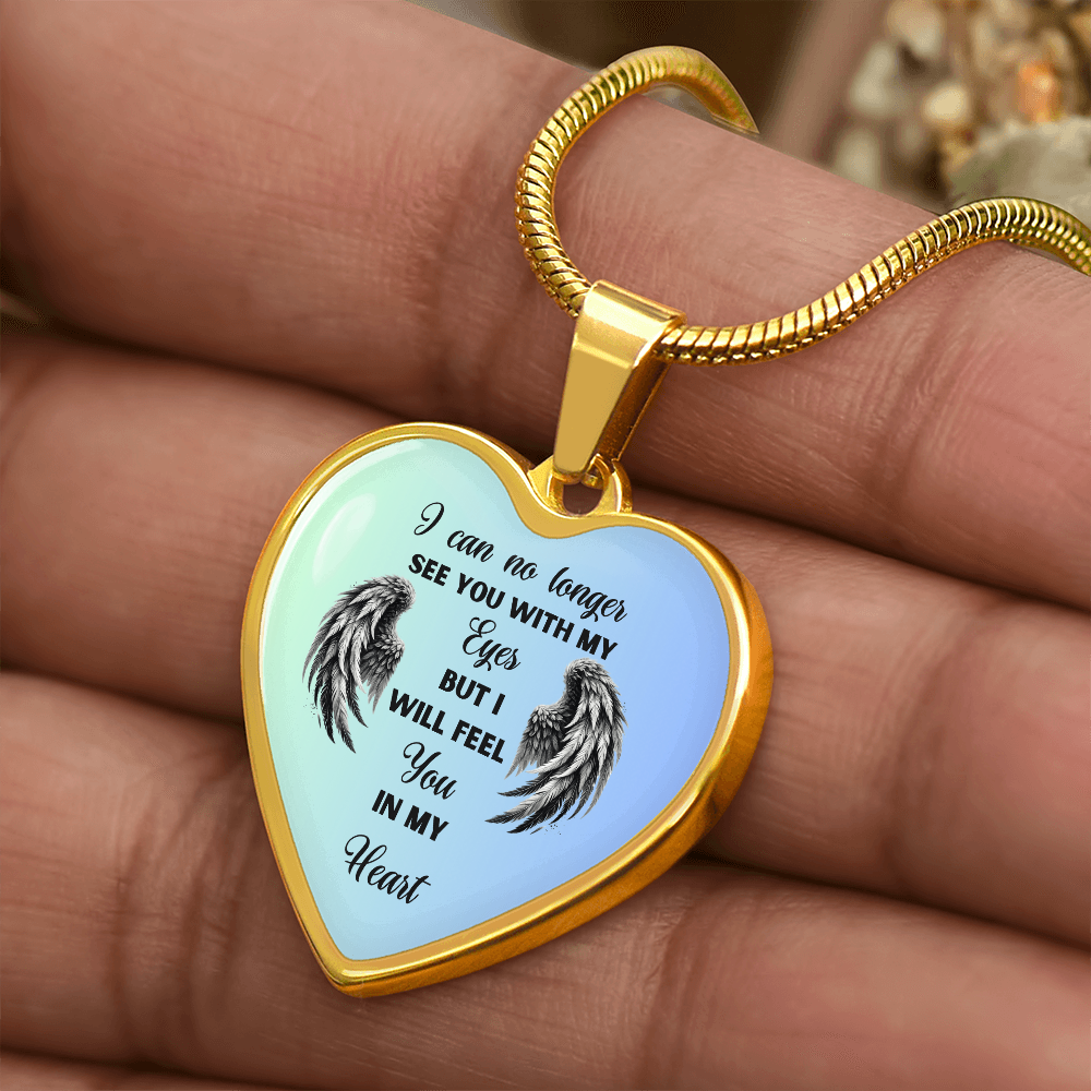 Gold heart-shaped pendant necklace with black angel wings and sentimental text on a light blue background.