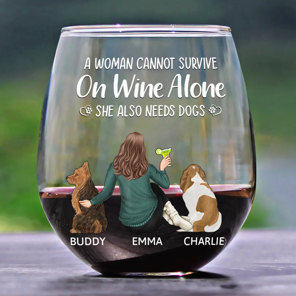 Wine glass with "A Woman Cannot Survive On Wine Alone. She Also Needs Dogs" text, woman with cocktail, two dogs, and personalized names.