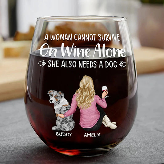 A large glass of red wine with a white design depicting a woman, "Amelia," with blonde hair and a pink sweater, sitting next to a dog, "Buddy," under the text "A WOMAN CANNOT SURVIVE On Wine Alone SHE ALSO NEEDS A DOG".