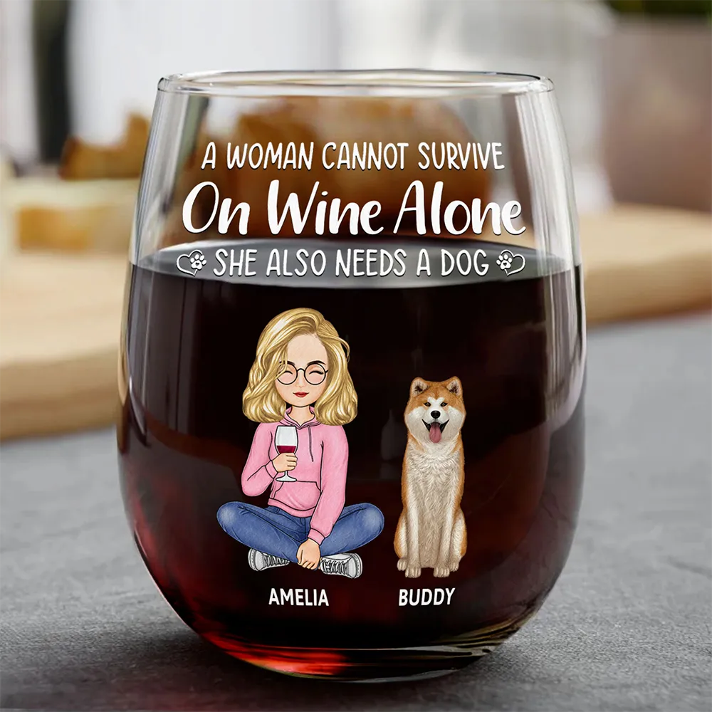 Wine glass with cartoon woman and dog design, text "A woman cannot survive on wine alone she also needs a dog" on clear glass, red wine inside.