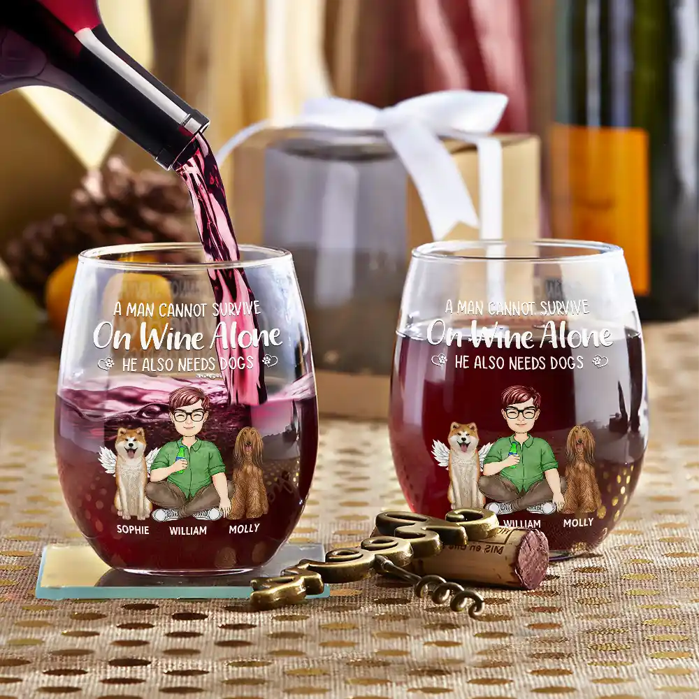 A close-up studio shot shows two wine glasses filled with red wine, personalized with cartoon drawings of a man and two dogs with names below them, accompanied by a gold-toned corkscrew and wine stopper on a gold patterned surface, with blurred bottles and gift boxes in the background.