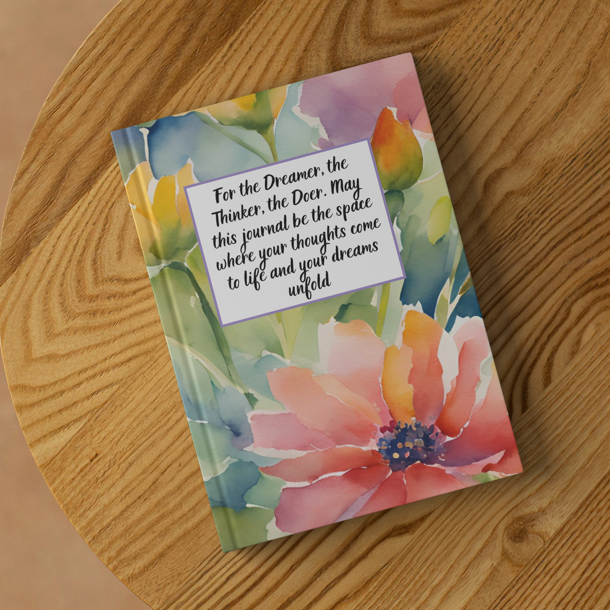 Colorful floral journal with inspirational quote on front, placed on wooden surface.