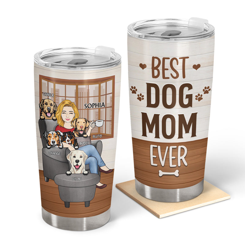 Two customized stainless steel tumblers. One has a woman with five dogs sitting in a chair. The other has the phrase "Best Dog Mom Ever" written on it. The tumbler with the phrase on it is sitting on a small square coaster.