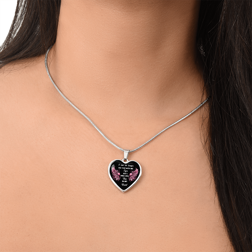 Silver heart pendant necklace with black center and pink and white sentimental text worn on a woman's neck.