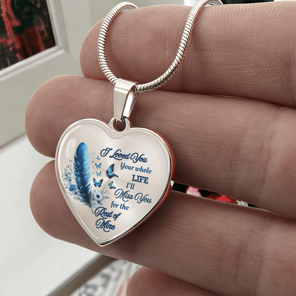 Silver heart-shaped pendant necklace with blue feather and engraved sentimental text on white background.