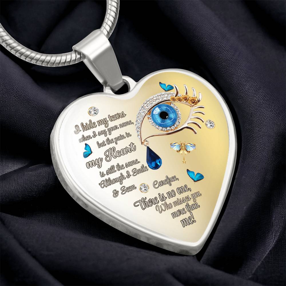 Heart-shaped silver necklace pendant with a blue eye, teardrop, butterflies, and engraved poetic text.