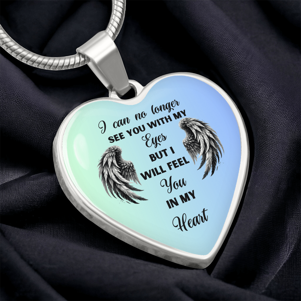 Silver heart pendant with angel wings and blue and green background displaying the text "I can no longer see you with my eyes but I will feel you in my heart".