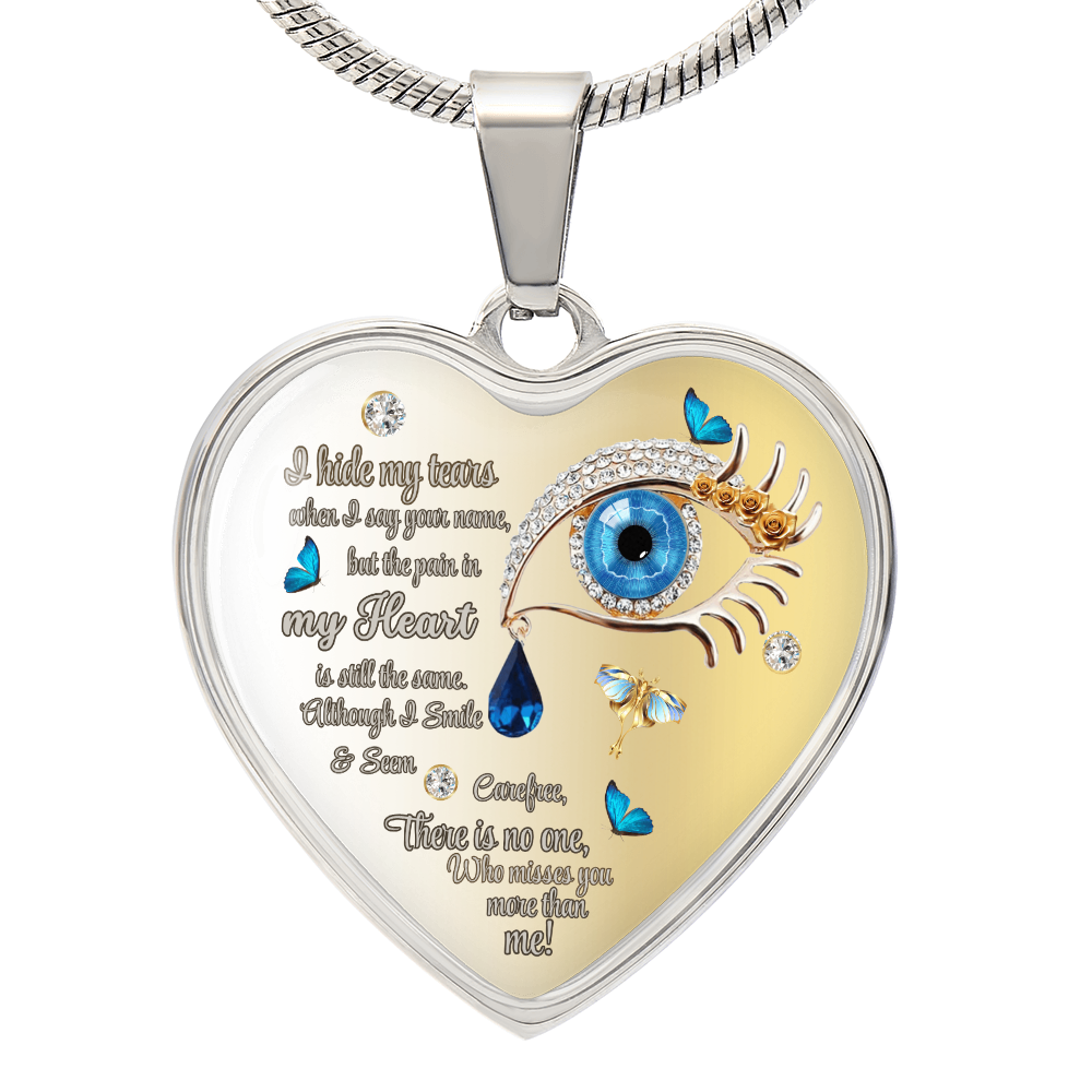 Silver heart-shaped necklace pendant with blue eye and tear graphic, inscribed emotional text.