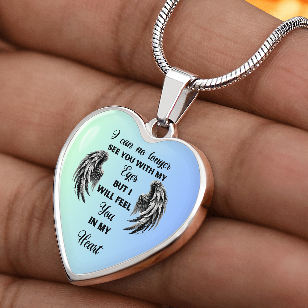 Silver heart-shaped necklace pendant with angel wings and inscription on light blue background.