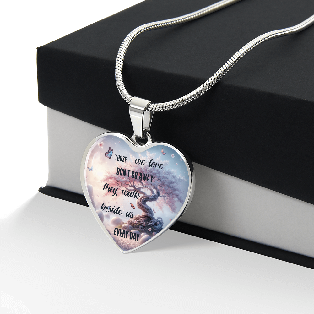 Silver heart-shaped pendant necklace with engraved sentimental message and artistic pink and blue background on black and.