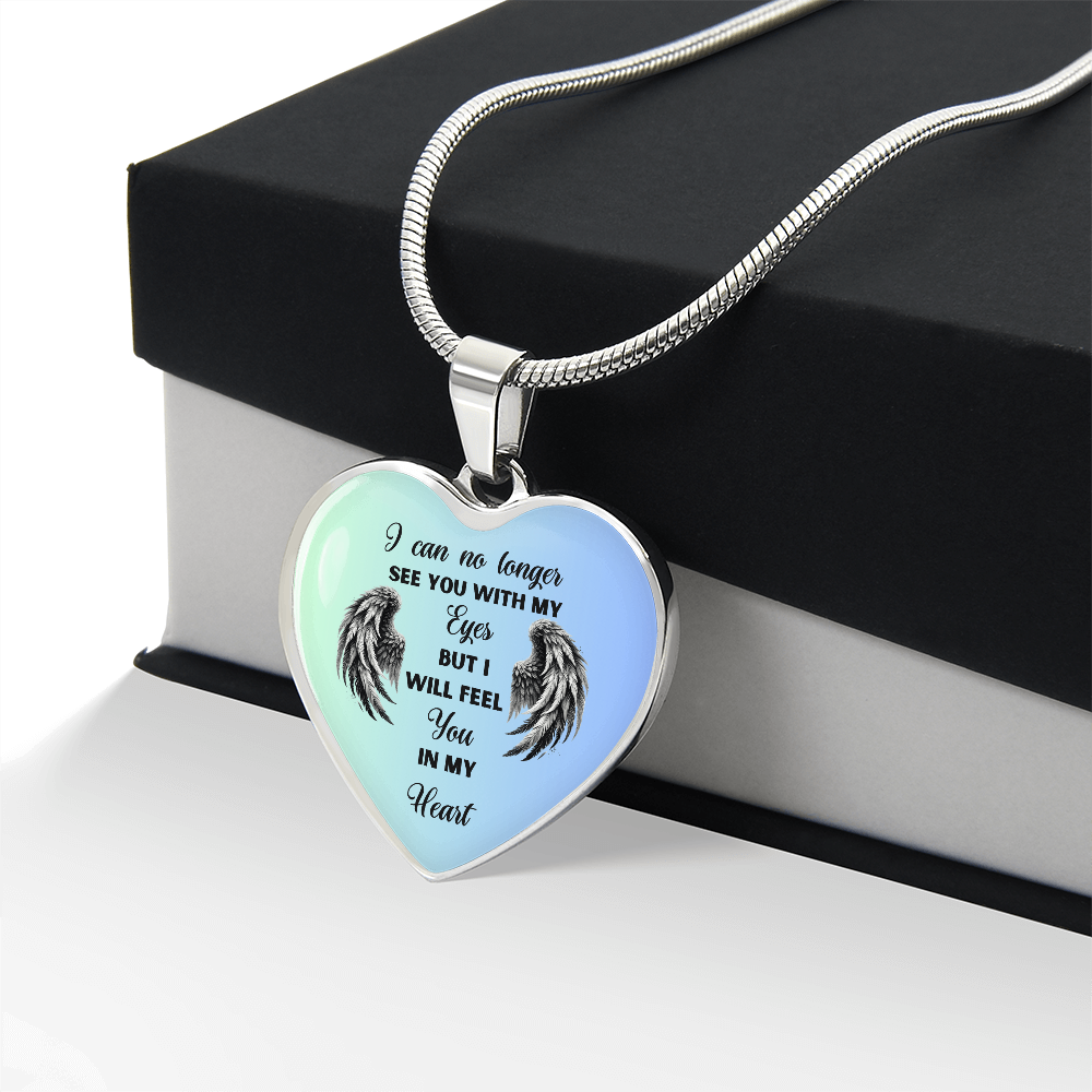 Heart-shaped pendant necklace with angel wings and memorial quote on a black box.
