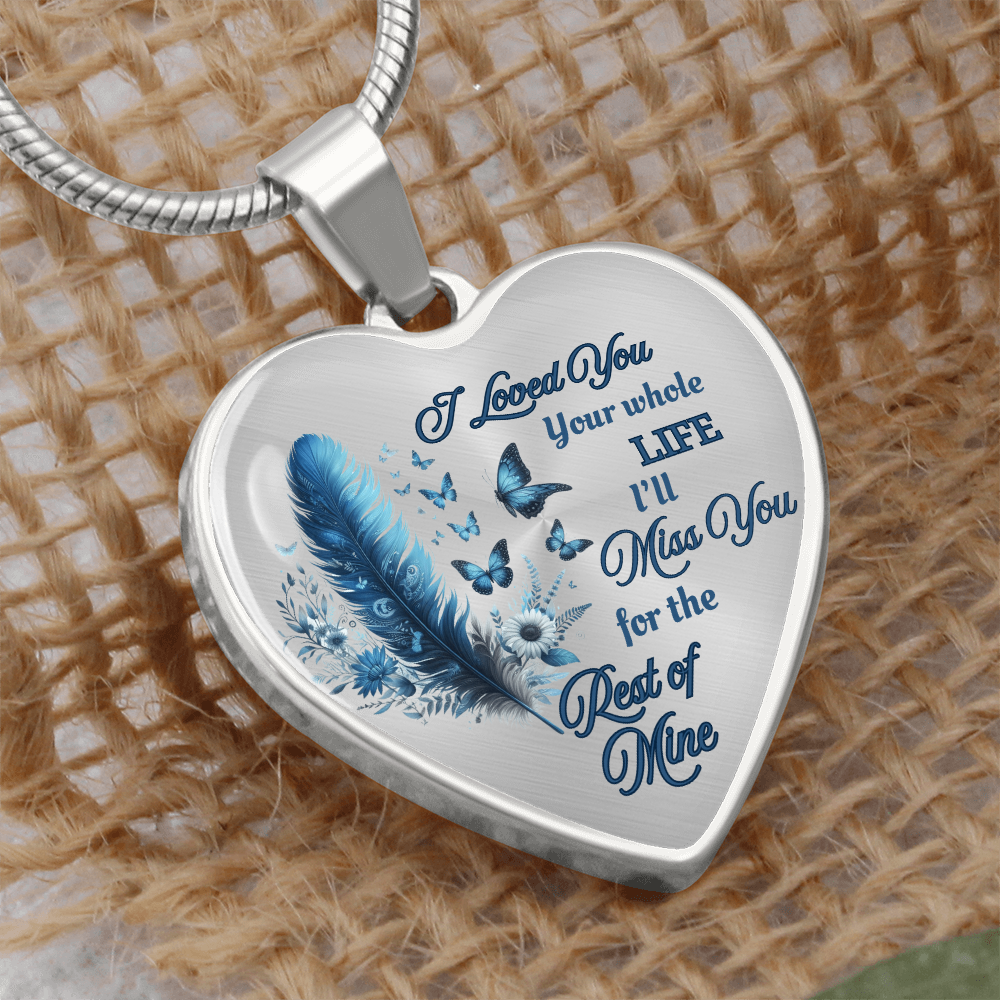 Silver heart-shaped pendant necklace with blue feather, butterflies, and engraved sentimental text.