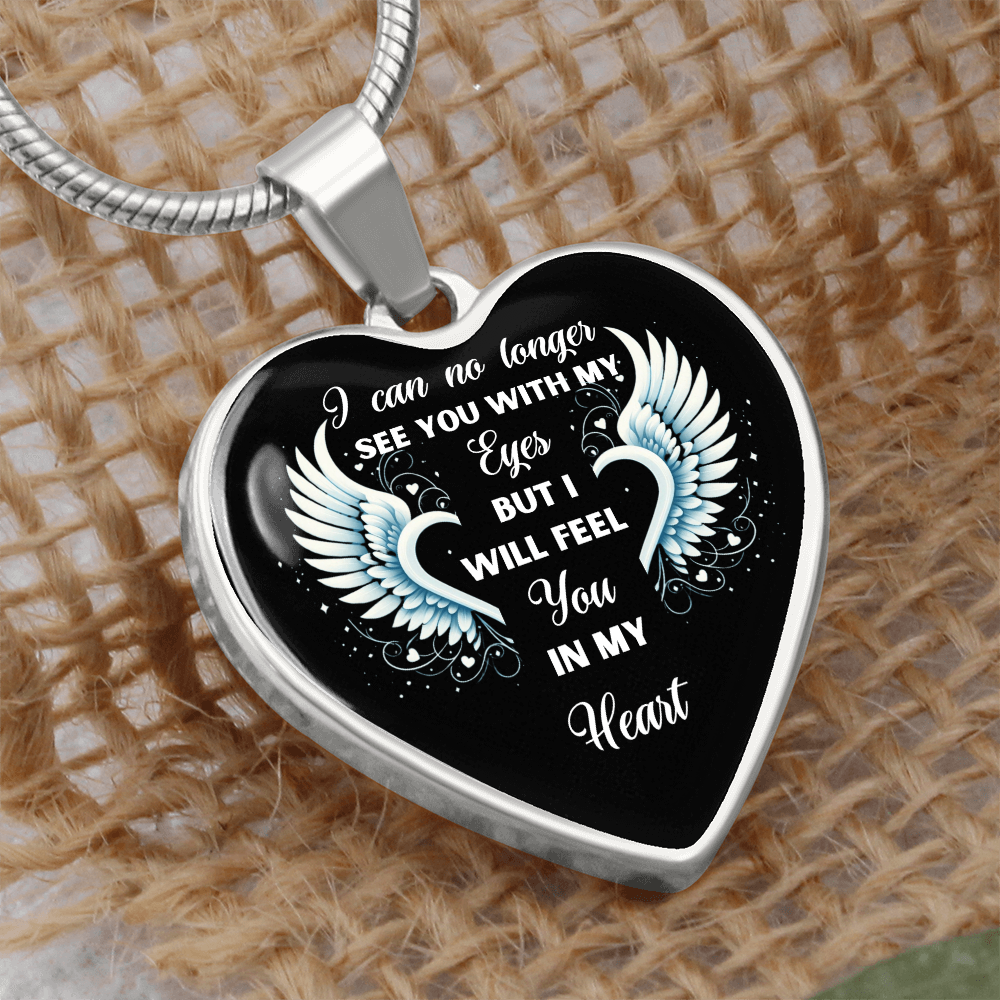Silver heart-shaped pendant necklace with white angel wings and sentimental quote on black background.