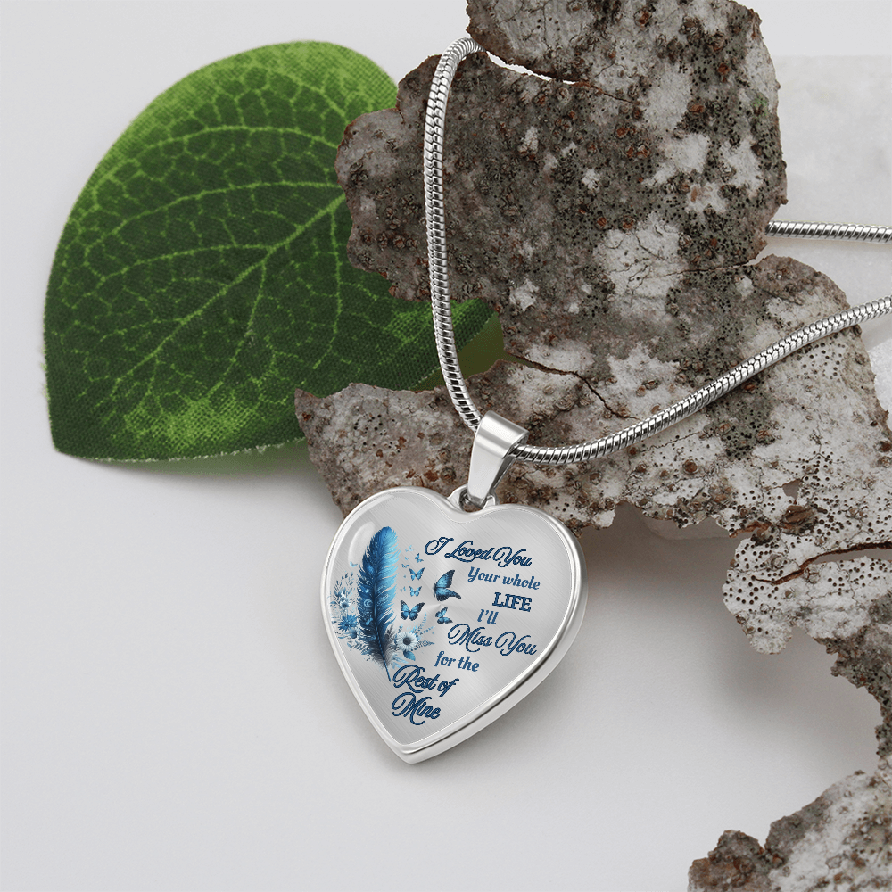 Silver heart-shaped pendant necklace with blue feather and engraved sentimental text.