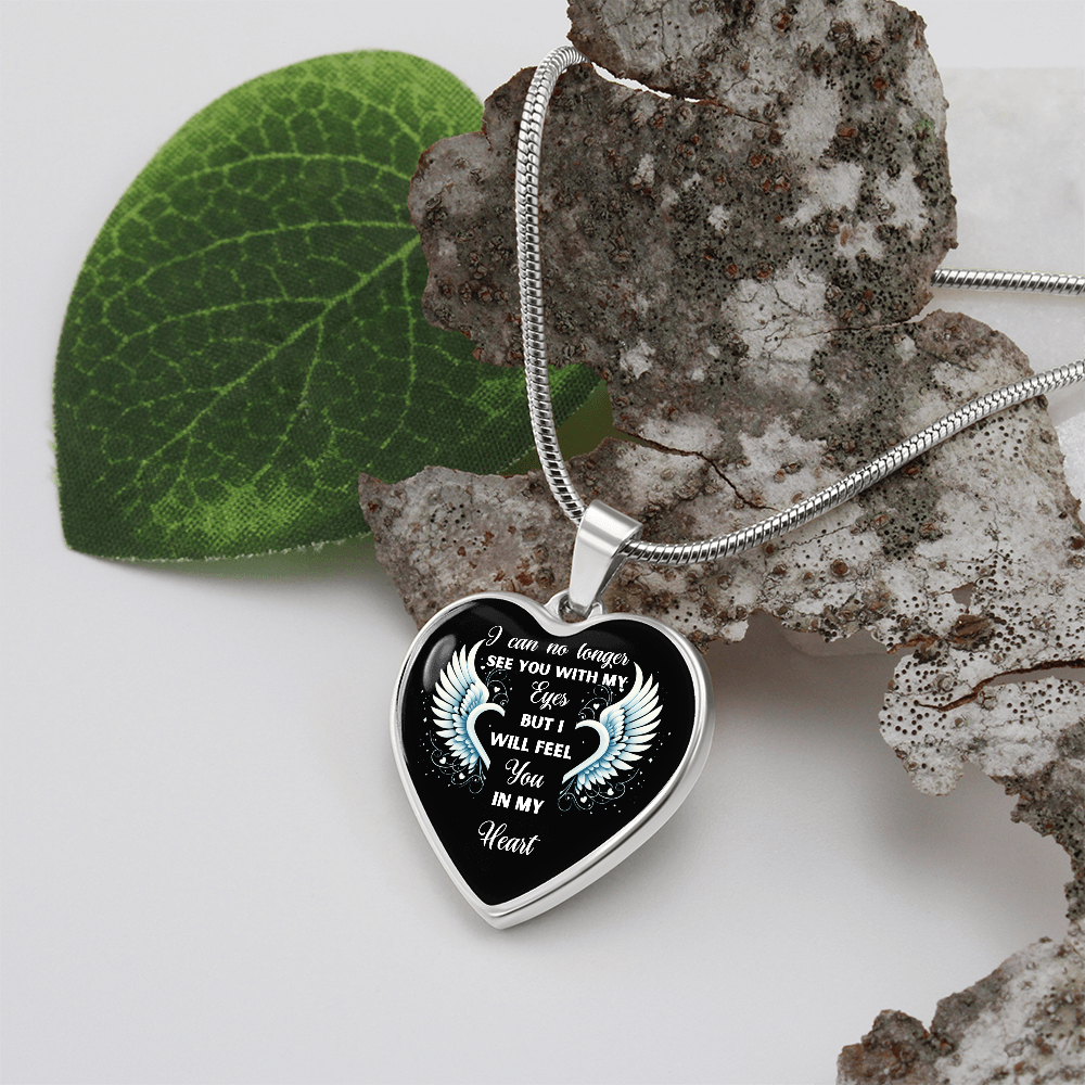 Silver heart-shaped pendant necklace with engraved memorial message and laurel design on black background.