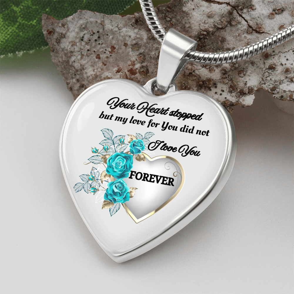 Silver heart-shaped pendant with blue rose design and engraved memorial message on snake chain.