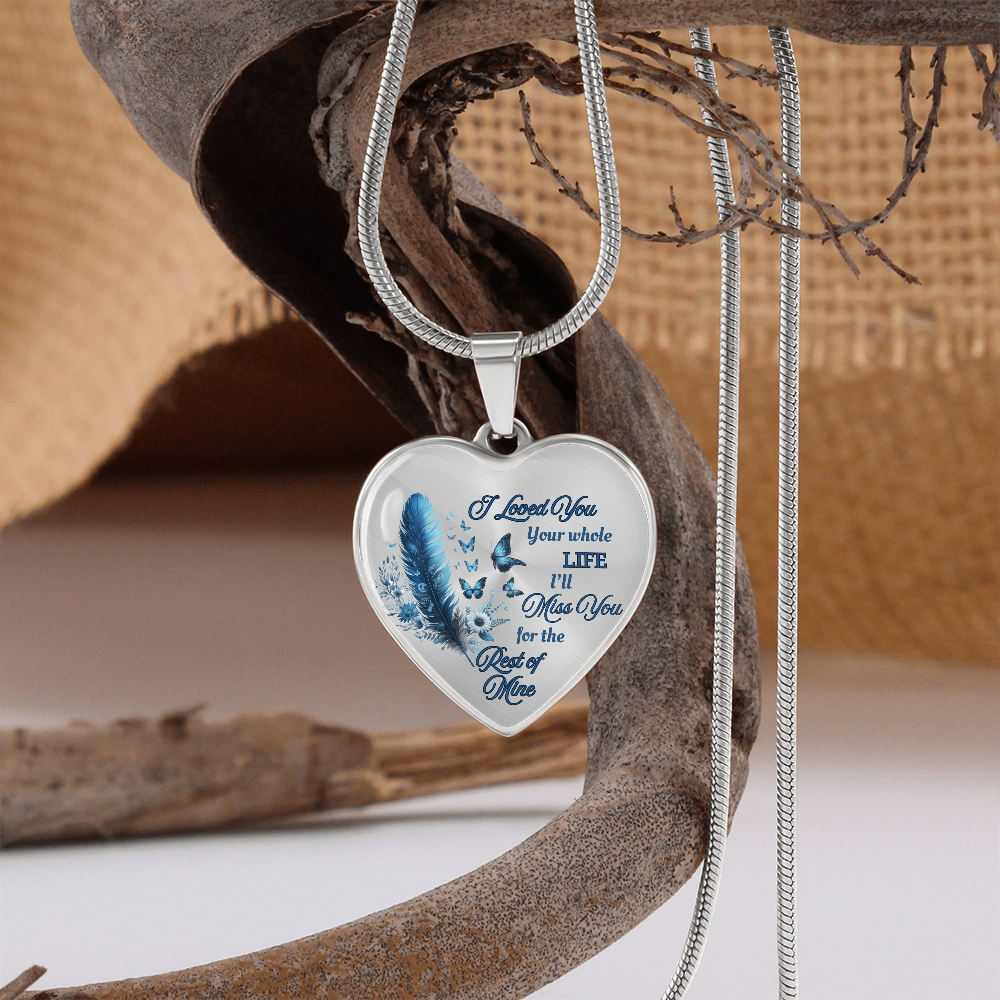 Silver heart-shaped pendant necklace with blue feather and engraved love message.