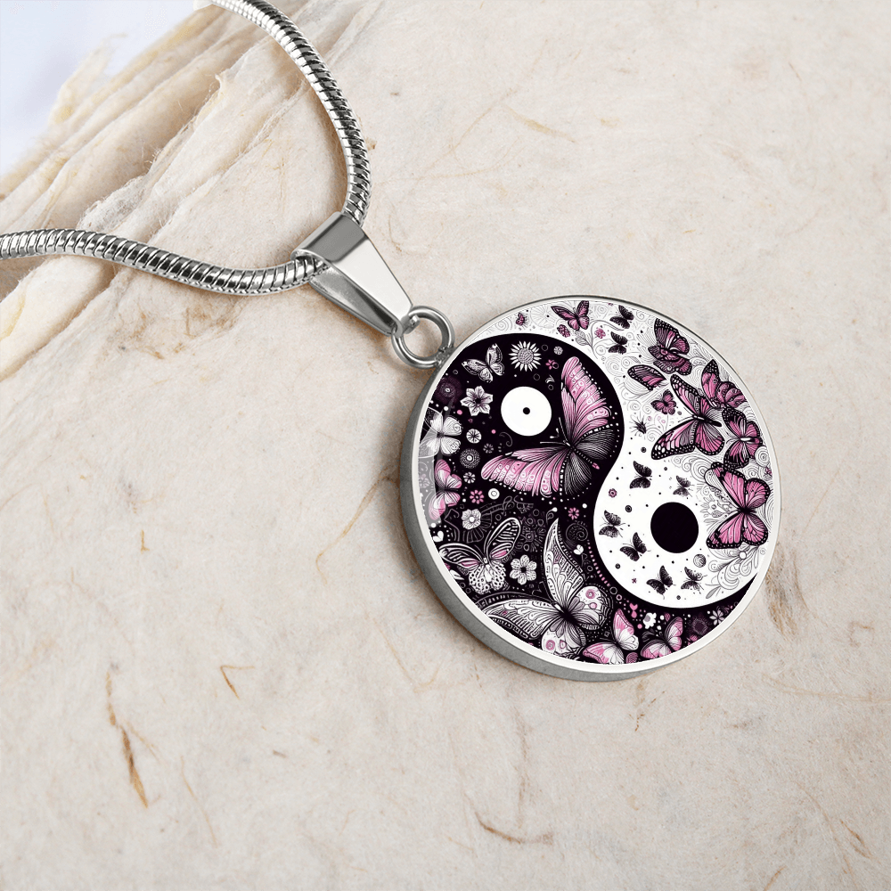 Silver round pendant featuring a yin yang symbol decorated with violet butterflies on a snake chain necklace.