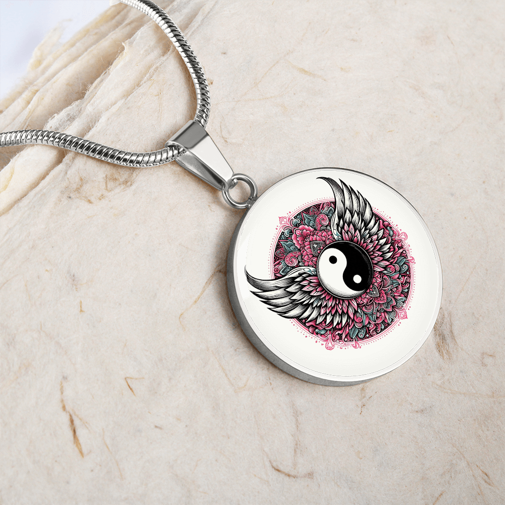 Silver circle necklace pendant with yin yang symbol, surrounded by pink floral design and angel wings.