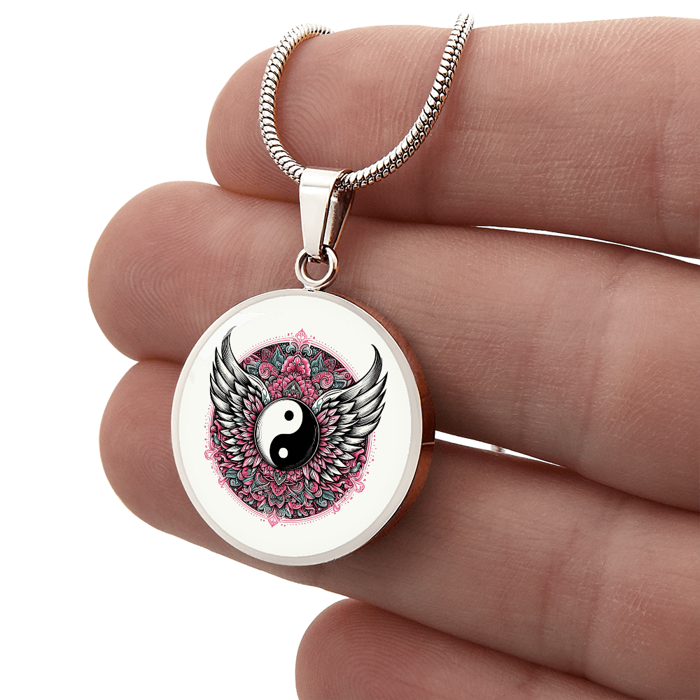 Silver round necklace pendant featuring black and white yin yang symbol with detailed angel wings and pink floral background.