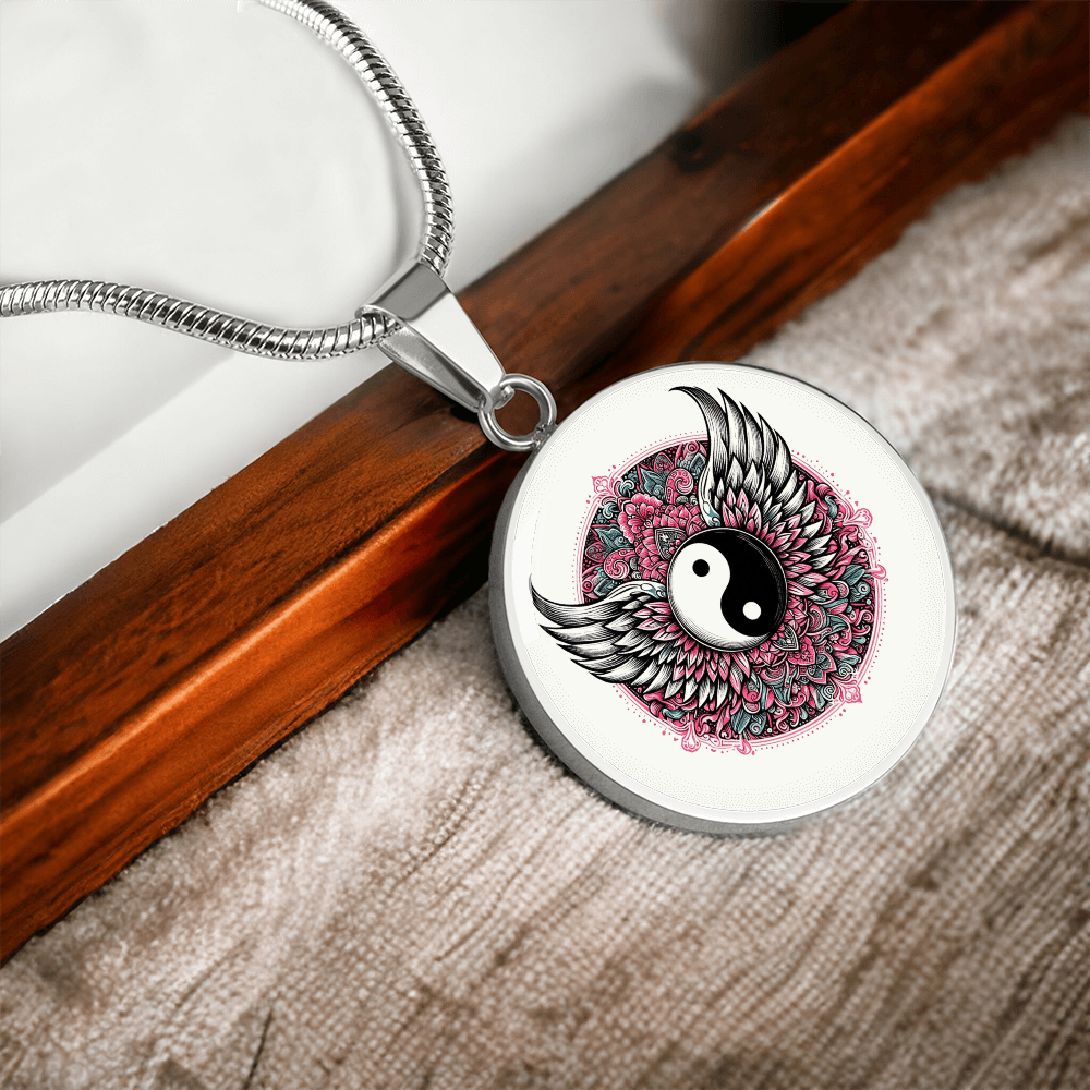 Silver circular pendant necklace with yin yang symbol, angel wings, and pink floral design.