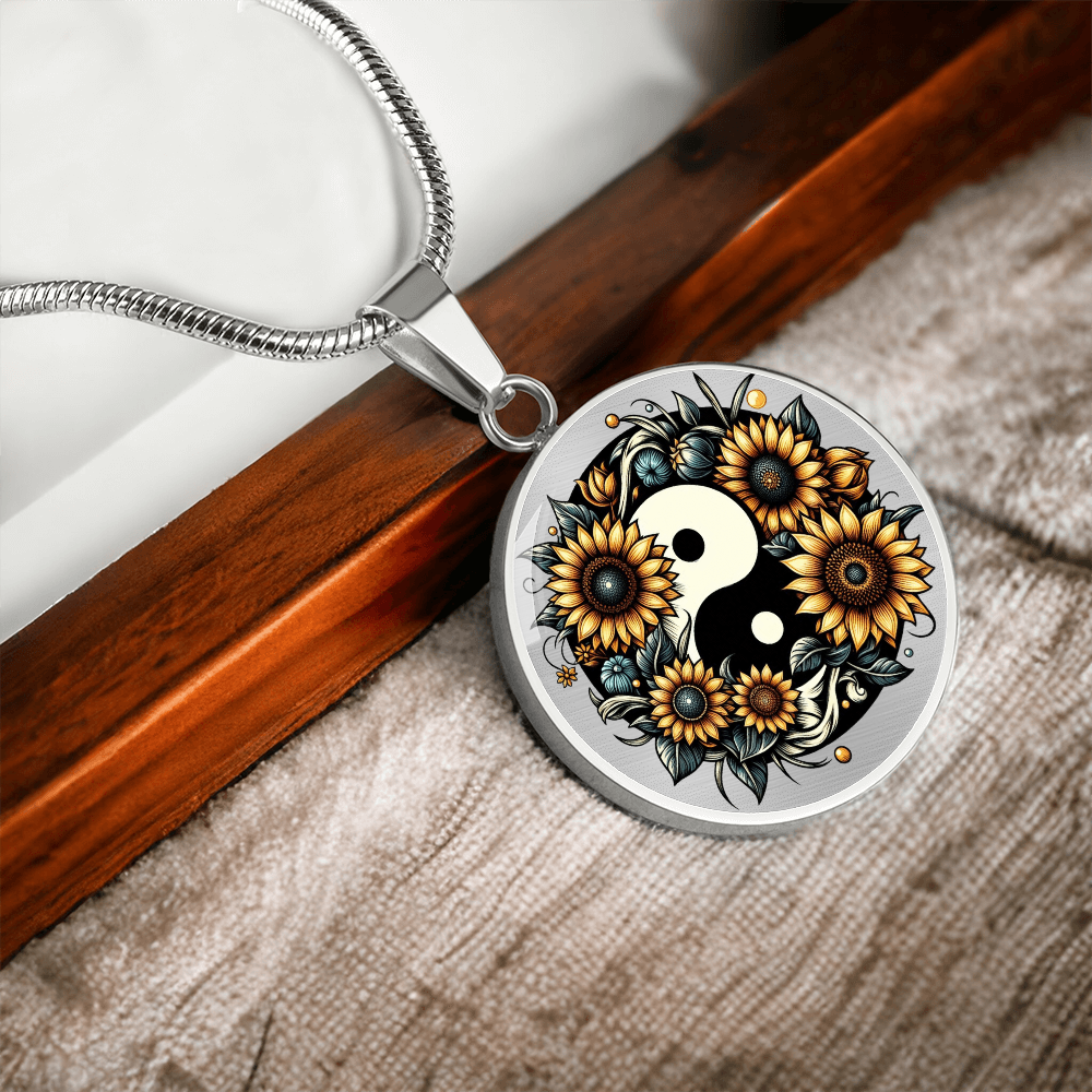 Silver circular pendant necklace featuring a yin yang symbol surrounded by detailed yellow sunflowers and green leaves.