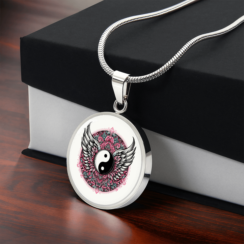 Silver round pendant necklace with yin yang symbol, angel wings, and pink floral background.