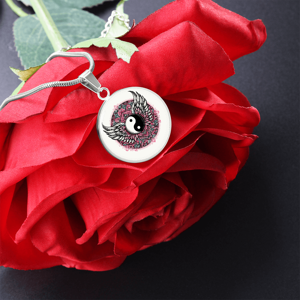Silver circle necklace pendant with black and white yin yang symbol surrounded by detailed angel wings on chain.