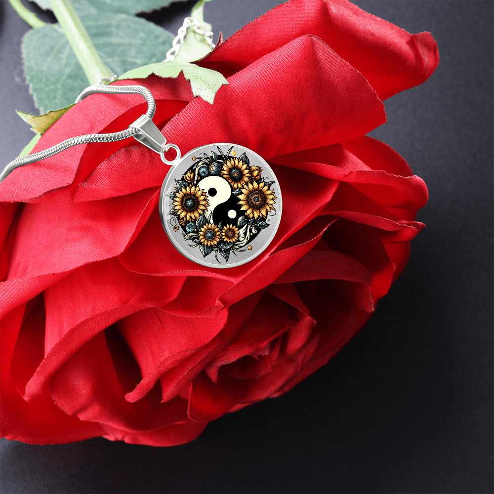 Silver circular necklace pendant with yin yang design of detailed black and yellow sunflowers on red rose background.