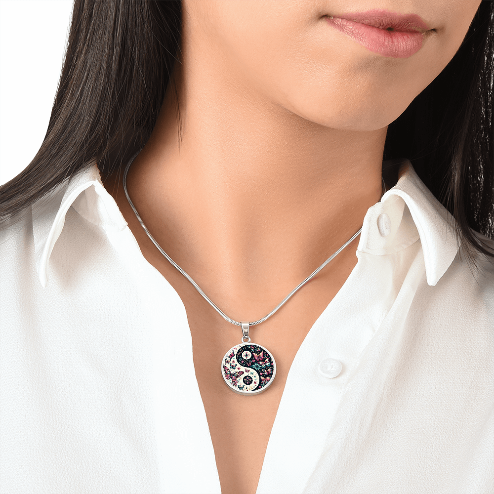 A woman wearing a yin yang butterfly pendant necklace. She is wearing a white blouse.