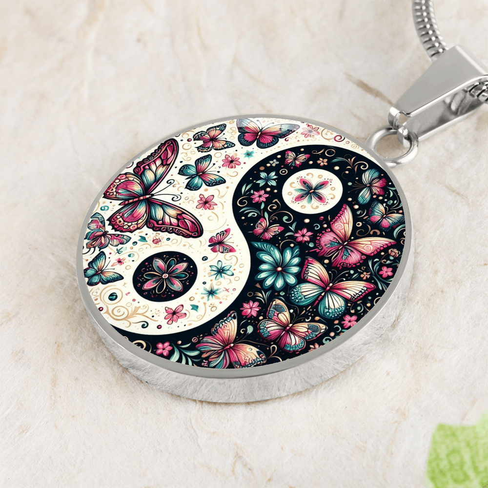 Close-up of a Yin and Yang pendant with a butterfly and floral design, silver chain, on a textured background.