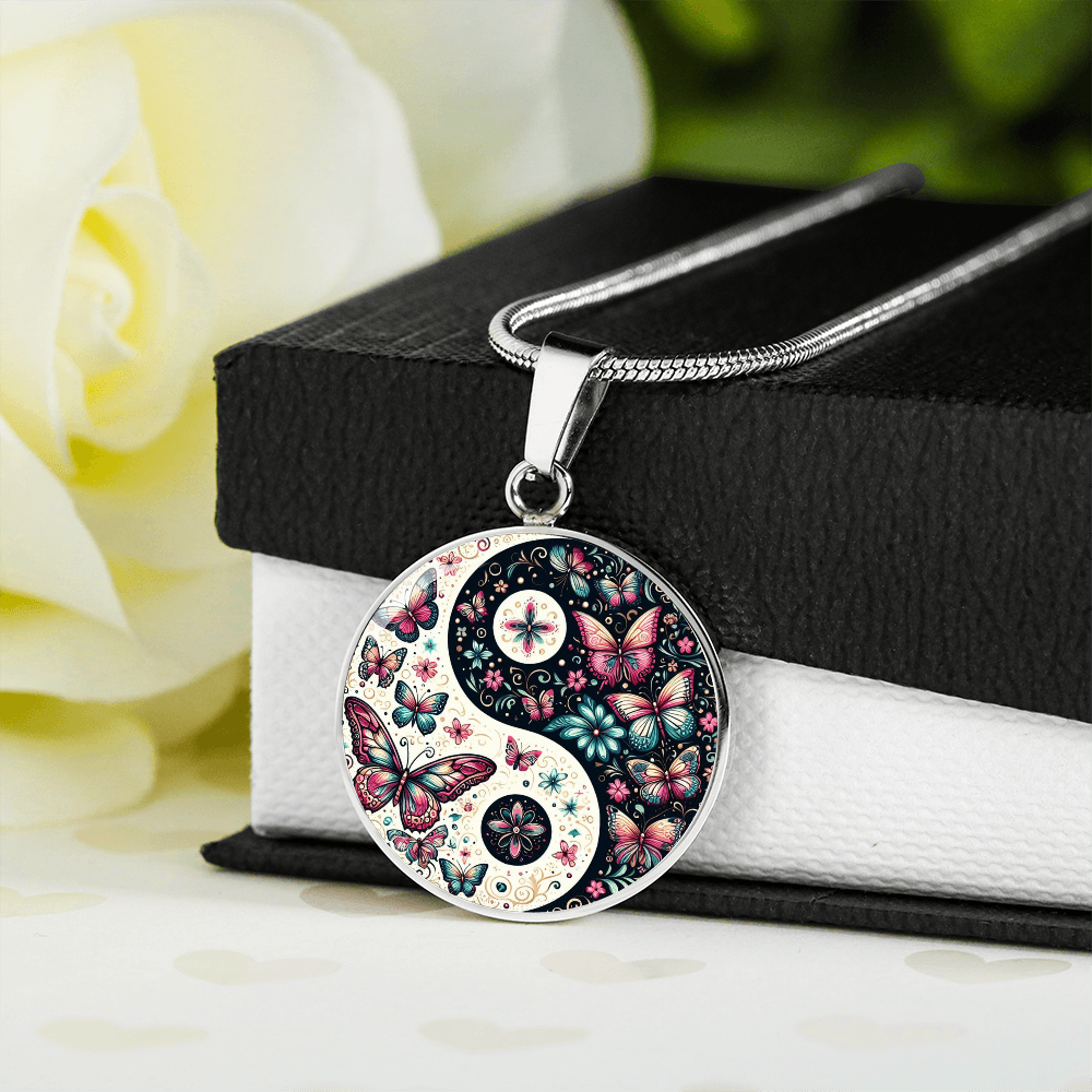 Necklace with a yin and yang design filled with butterflies and flowers.
