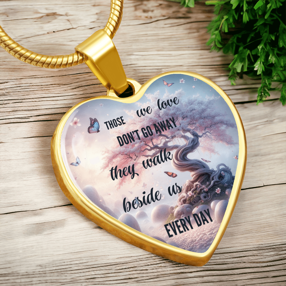 Gold heart-shaped pendant necklace with tree and butterfly design and sentimental quote.