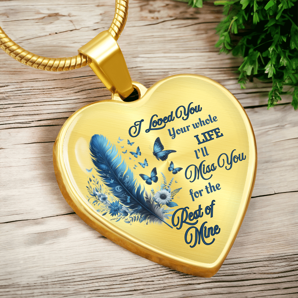 Gold heart-shaped pendant with blue feather, butterflies, and engraved sentimental message.
