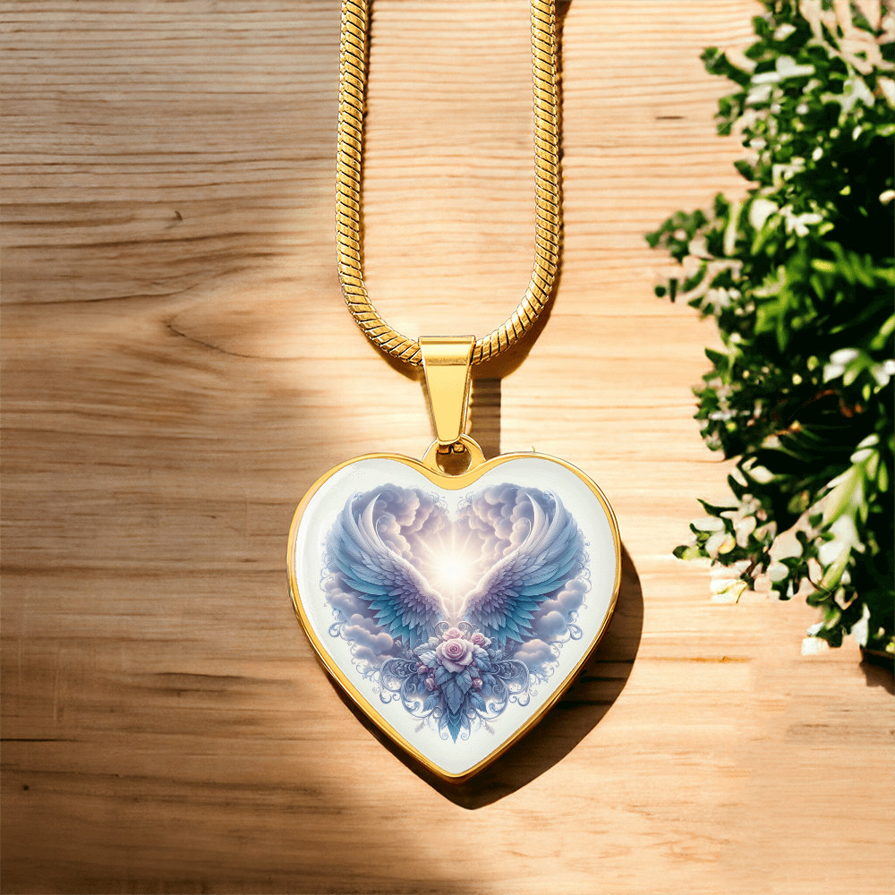Gold heart-shaped pendant necklace with angel wings graphic on wooden surface.