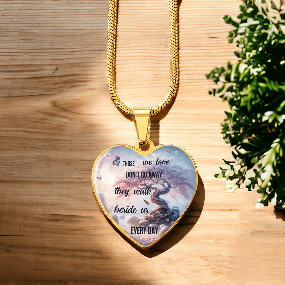 Gold heart-shaped pendant necklace with sentimental message over tree and sky background.