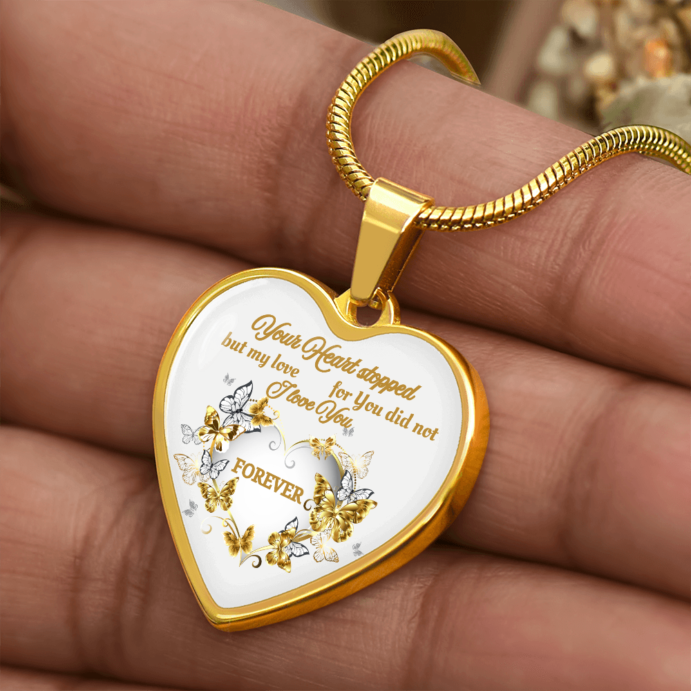 Gold heart pendant necklace with engraved sentimental message and butterfly details on white background.
