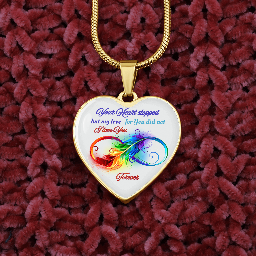Gold heart-shaped pendant necklace with colorful infinity design and blue and red script text on white background.