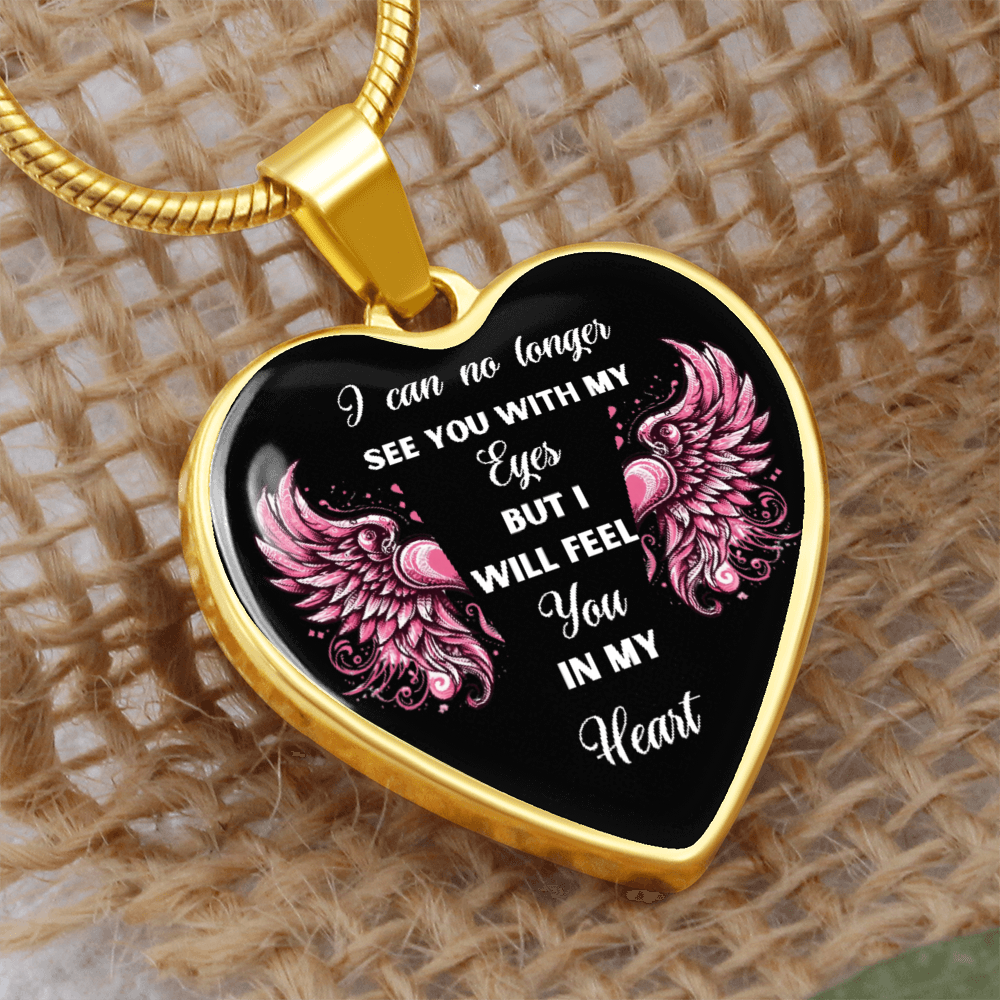 Gold heart-shaped pendant with pink angel wings and engraved sentimental message on black background, hanging on gold chain.