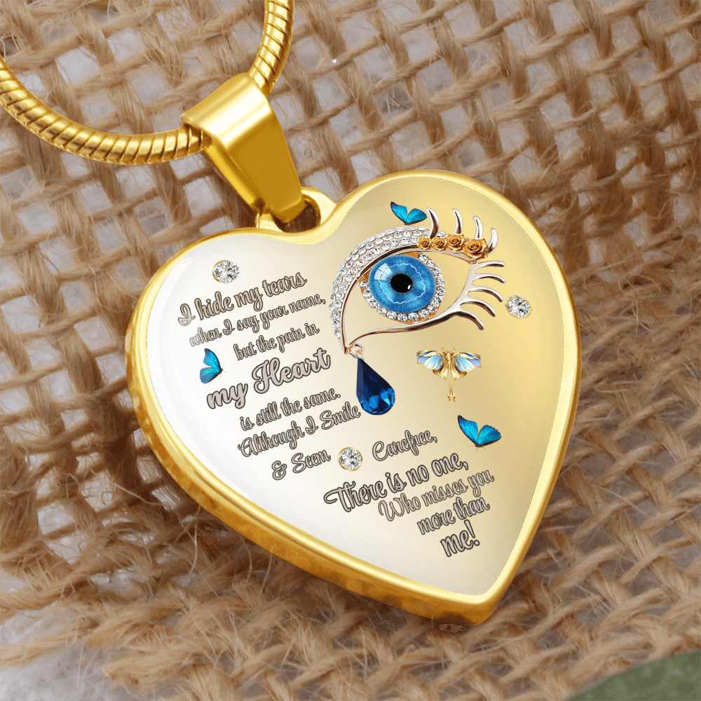 Gold heart-shaped necklace pendant with blue eye graphic, teardrop, and engraved sentimental text.