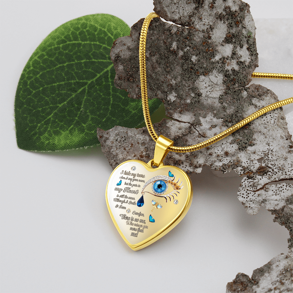 Gold heart pendant necklace with engraved blue eye, teardrops, and script text on a gold chain.