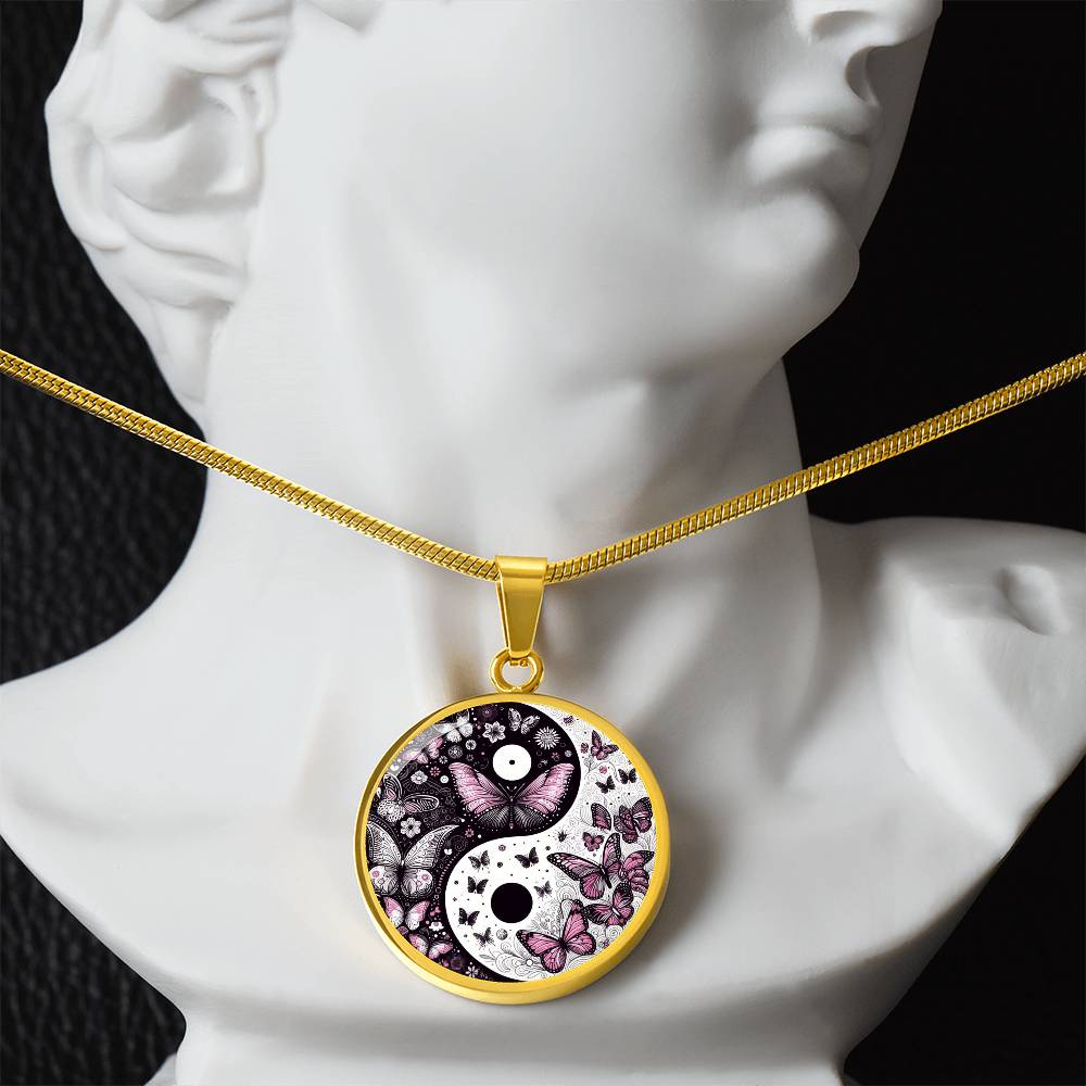 Gold pendant necklace with a yin yang symbol filled with butterflies, hanging on a white mannequin.