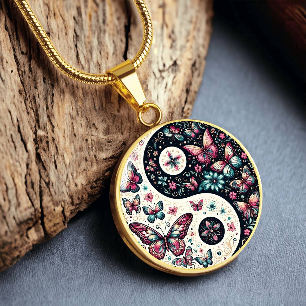 Gold circular yin yang necklace with pink and teal butterflies and intricate floral details.