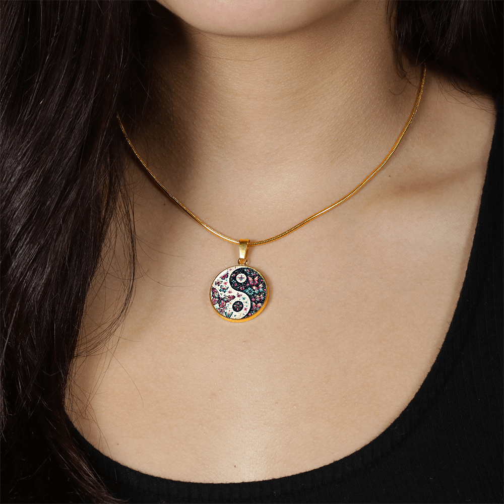 Gold necklace with pink butterfly yin yang circle pendant on model wearing black top.