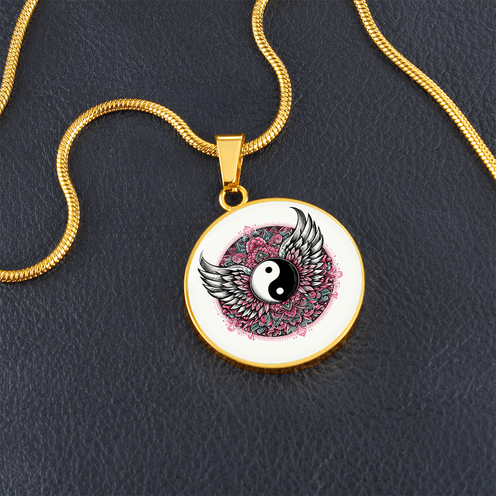 Gold circle necklace with yin yang symbol surrounded by detailed angel wings and pink accents.