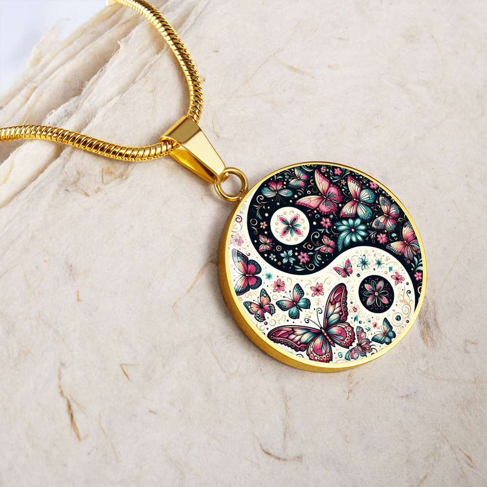 Gold circular yin yang pendant with pink and purple butterflies and floral accents on a gold chain.