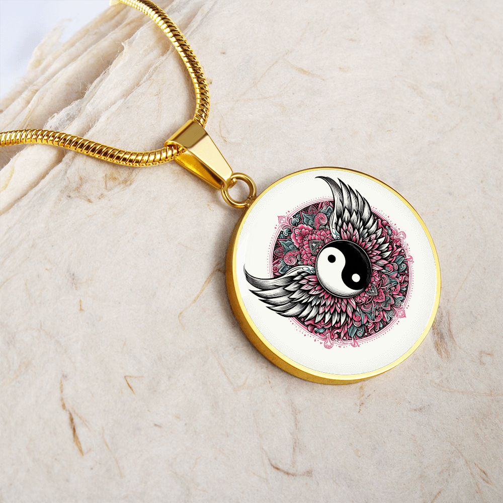 Gold circular pendant necklace featuring a black and white yin yang symbol with detailed angel wings and pink floral.